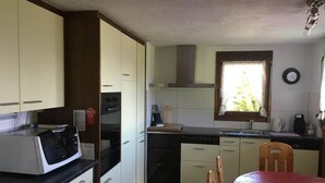 A compact kitchen with white cabinets, a microwave, a coffee maker, and a window with curtains.
