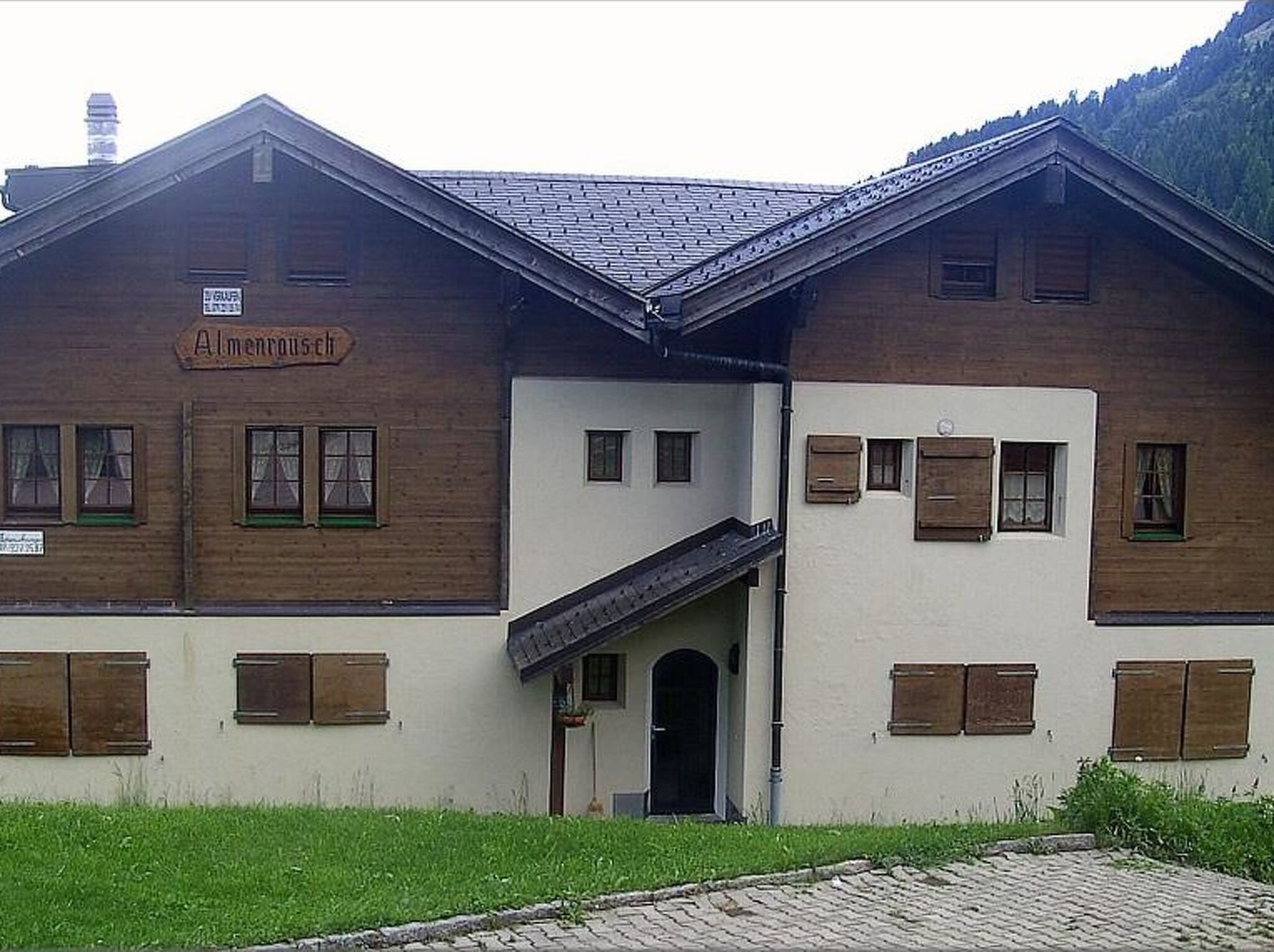 A two-story building with a sign reading "Almenroost".