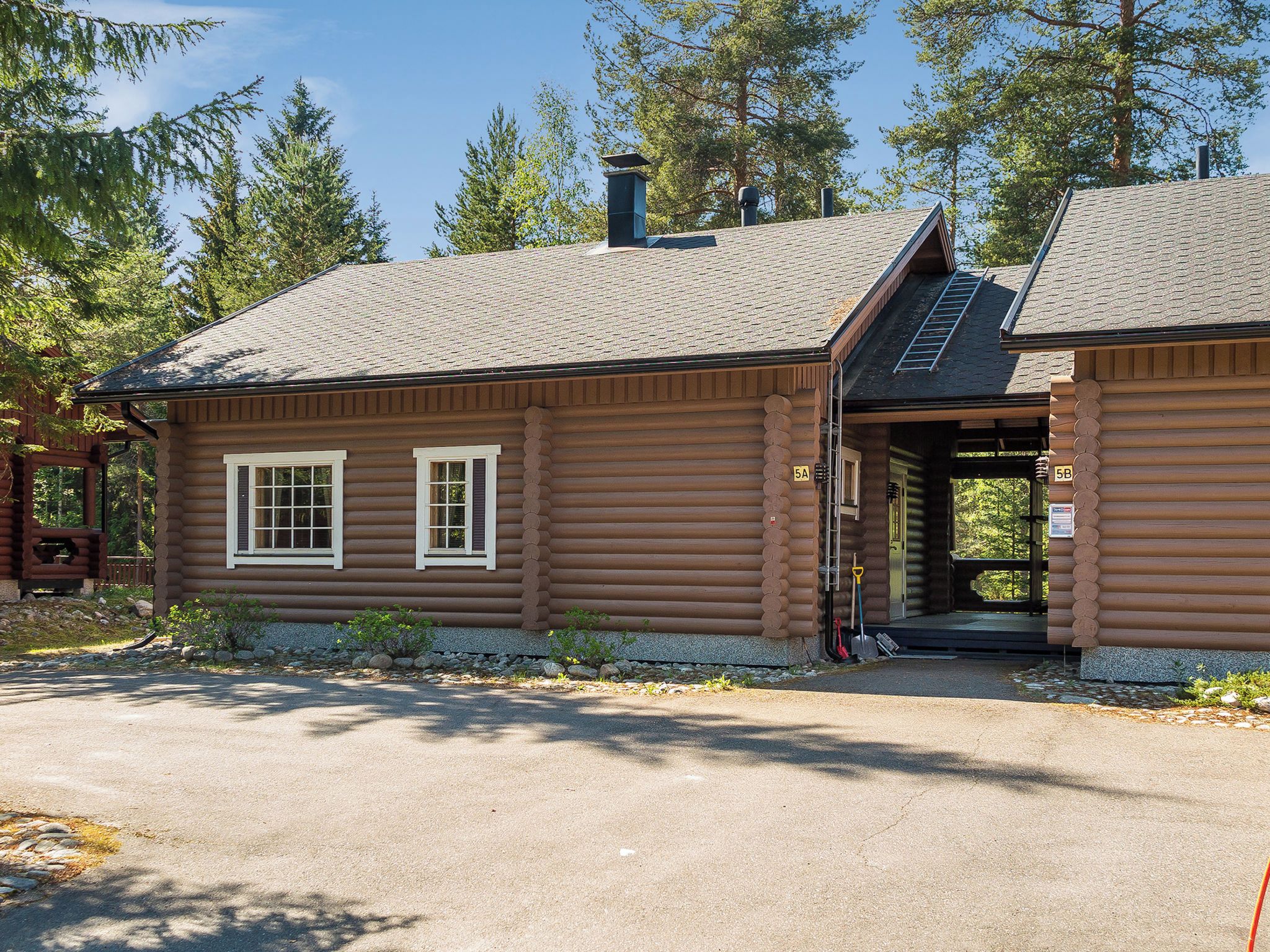 A log cabin with a chimney, two windows, and a covered porch.