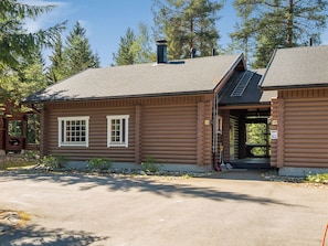 A log cabin with a chimney, two windows, and a covered porch.