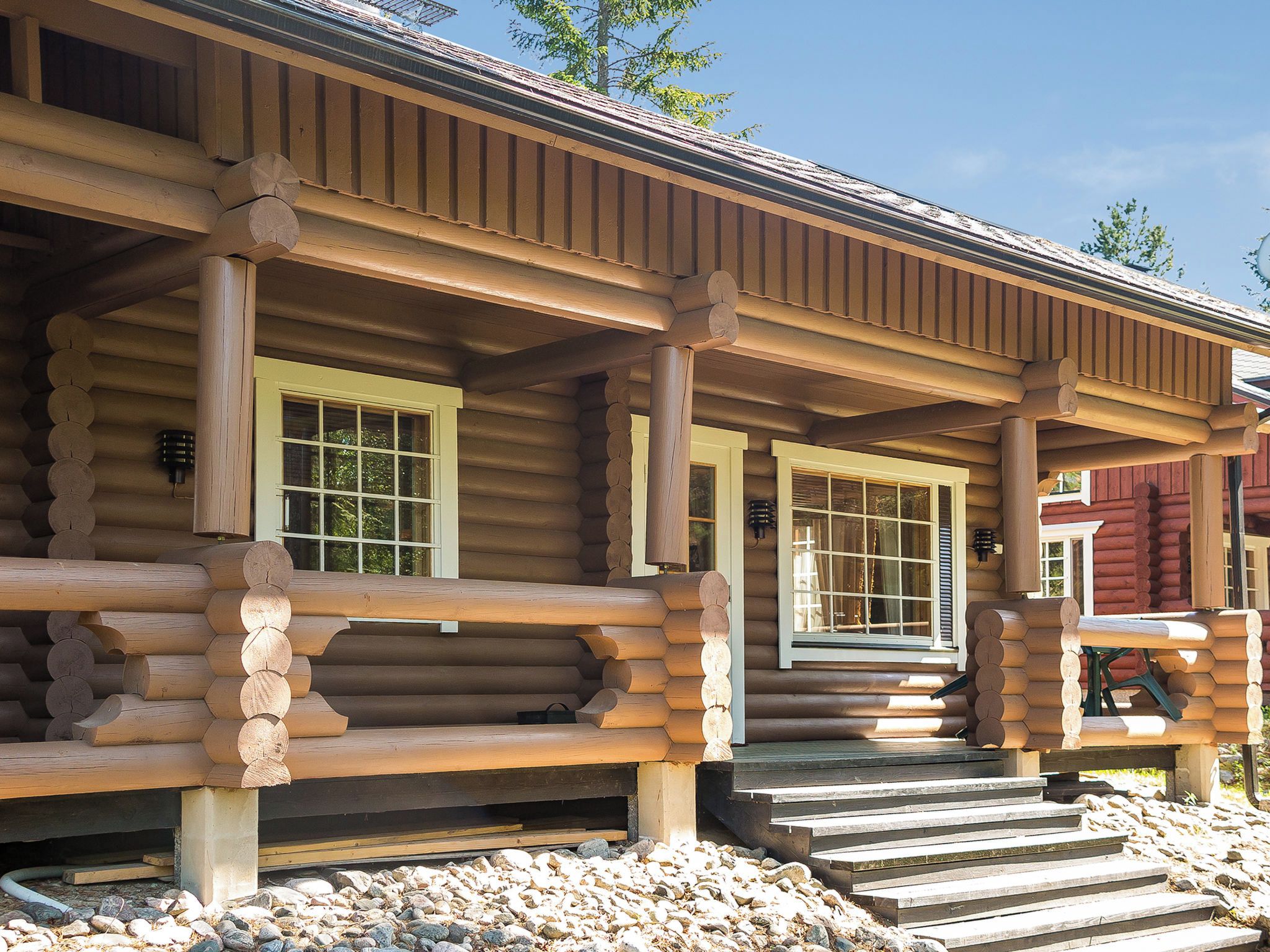 A log cabin with a porch, wooden steps, and a window.