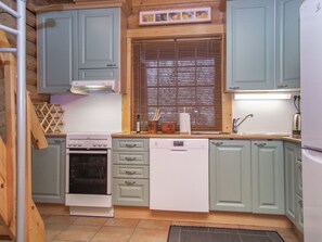 A compact kitchen with a built-in oven, a dishwasher, and light blue cabinets. - Tahkon tikka by Interhome (Nilsiä)