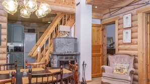 A cozy log cabin interior with a dining area, a fireplace, and a staircase. - Tahkon tikka by Interhome (Nilsiä)