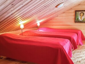 A room with two beds covered in red bedding, wooden walls, and a sloped ceiling with a skylight. - Tahkon tikka by Interhome (Nilsiä)