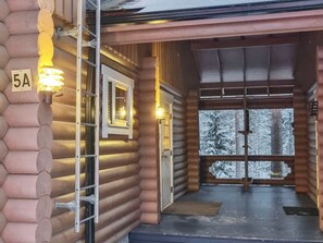 A log cabin entrance with a metal ladder, a door, and a window with a view of snow-covered trees. - Tahkon tikka by Interhome (Nilsiä)