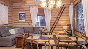 A cozy log cabin interior with a wooden staircase, a dining table with chairs, a sofa, and a chandelier. - Tahkon tikka by Interhome (Nilsiä)