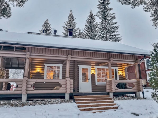 A log cabin with a porch, a front door, and a chimney.