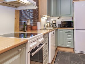 A kitchen with a stove, oven, microwave, and a coffee maker.