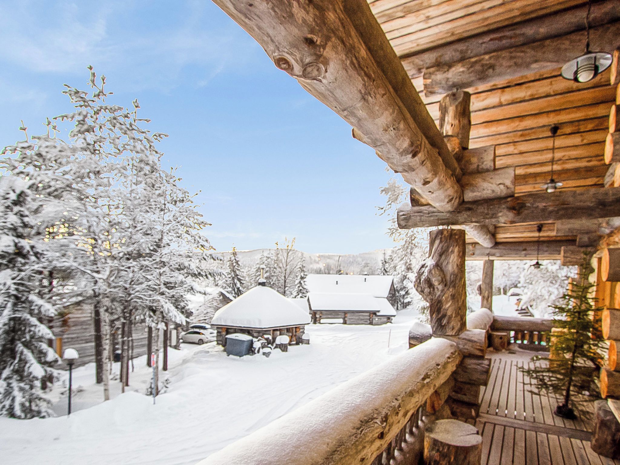 Une cabane en bois avec une terrasse enneigée et un ciel dégagé.