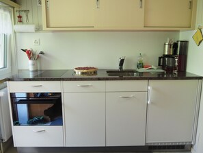 Eine Küche mit Mikrowelle, Kaffeemaschine und einer Pizza auf der Arbeitsfläche.