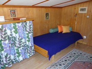 A bedroom with a bed, a desk, and a curtain.