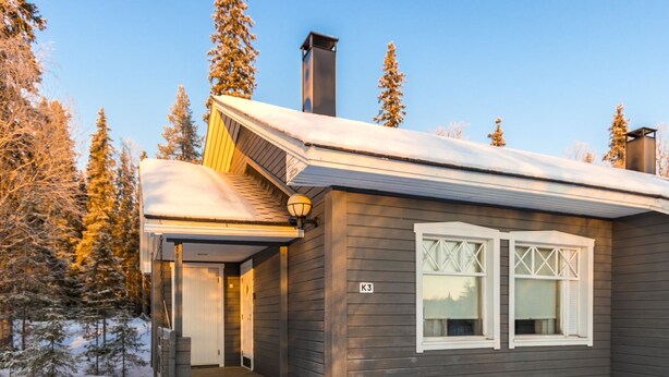 A wooden cabin with a covered porch, a chimney, and a window with shutters. - Tunturinvieri k3 by Interhome (Ylläsjärvi)