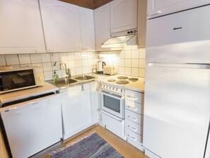 A compact kitchen with white cabinets, a built-in microwave, a dishwasher, a stove, and a refrigerator.
