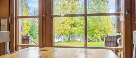 A wooden table with a view of a garden through a large window.