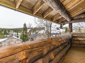 A log cabin with a wooden deck and a view of a snowy landscape.