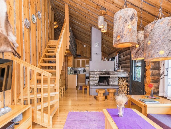 A wooden interior with a staircase, a fireplace, and a dining area.