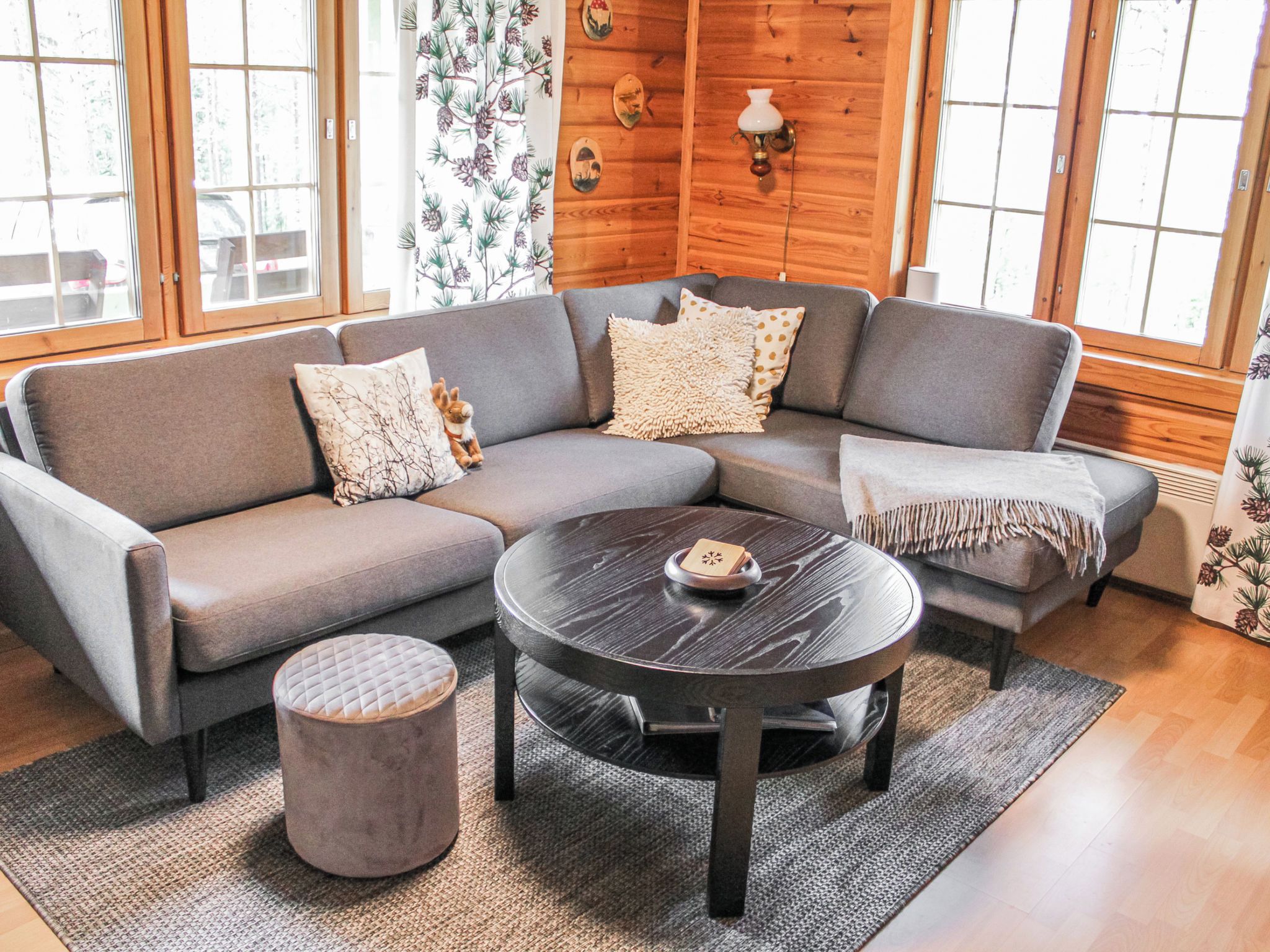 A modern living room with a sectional sofa, a round coffee table, and a small ottoman.