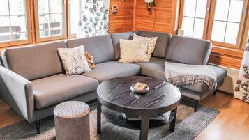 A modern living room with a sectional sofa, a round coffee table, and a small ottoman.
