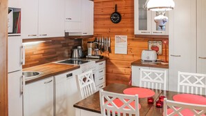 Una cocina compacta con armarios blancos, encimera de madera, estufa y una zona de comedor con mesa y sillas.