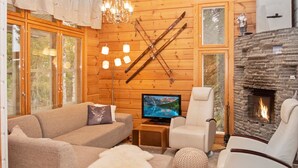 A cozy log cabin interior with a sofa, armchairs, a TV, a fireplace, and a ski rack. - Vuosseli-kelkka 15a by Interhome (Kuusamo)