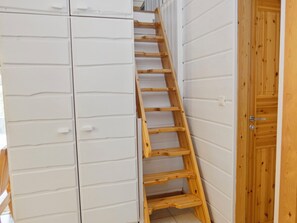 Una escalera de madera que conduce a una escalera en una habitación con paredes blancas y una puerta de madera.