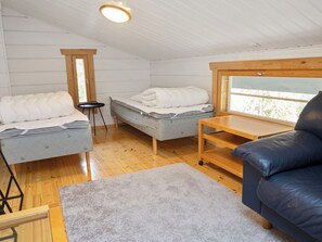 A compact room with two beds, a sofa, a small table, and a window.