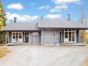 A two-story building with a gravel driveway, a covered porch, and a chimney.
