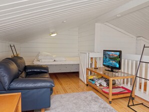 Una habitació acollidora amb un llit, un sofà de cuir, una televisió sobre un suport i un paviment de fusta.