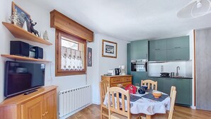 Un espace de vie compact comprenant un coin repas, une kitchenette et un meuble pour les appareils multimédias.