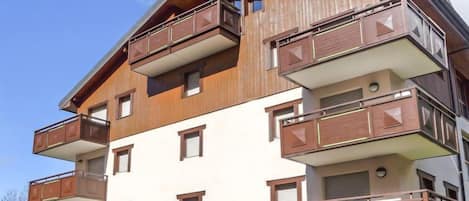 Un edificio de varios pisos con balcones, techo plano y cielo despejado.