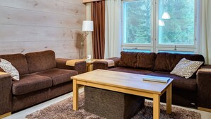 A cozy living room with two brown sofas, a wooden coffee table, and a window with blinds. - Weekend family by Interhome (Sotkamo)