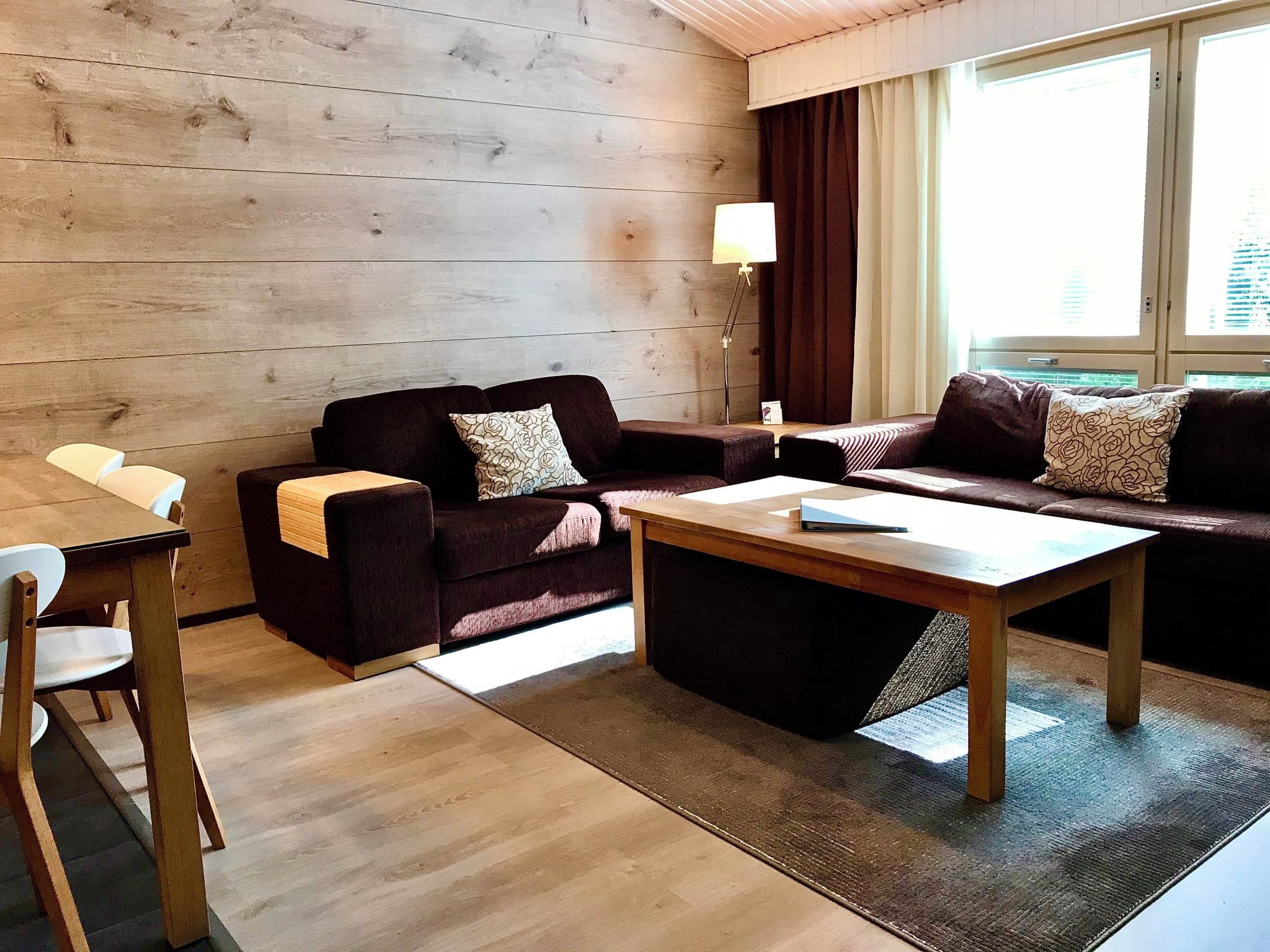 Un salon moderne avec deux canapés sombres, une table basse en bois et une table à manger avec des chaises.