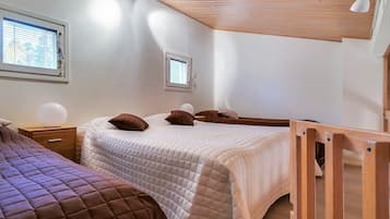 A bedroom with two beds, a wooden ceiling, and a window.