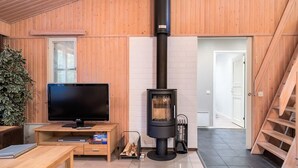 A modern living room with a large TV, a wooden TV stand, a fireplace, and a staircase. - Weekend family by Interhome (Sotkamo)