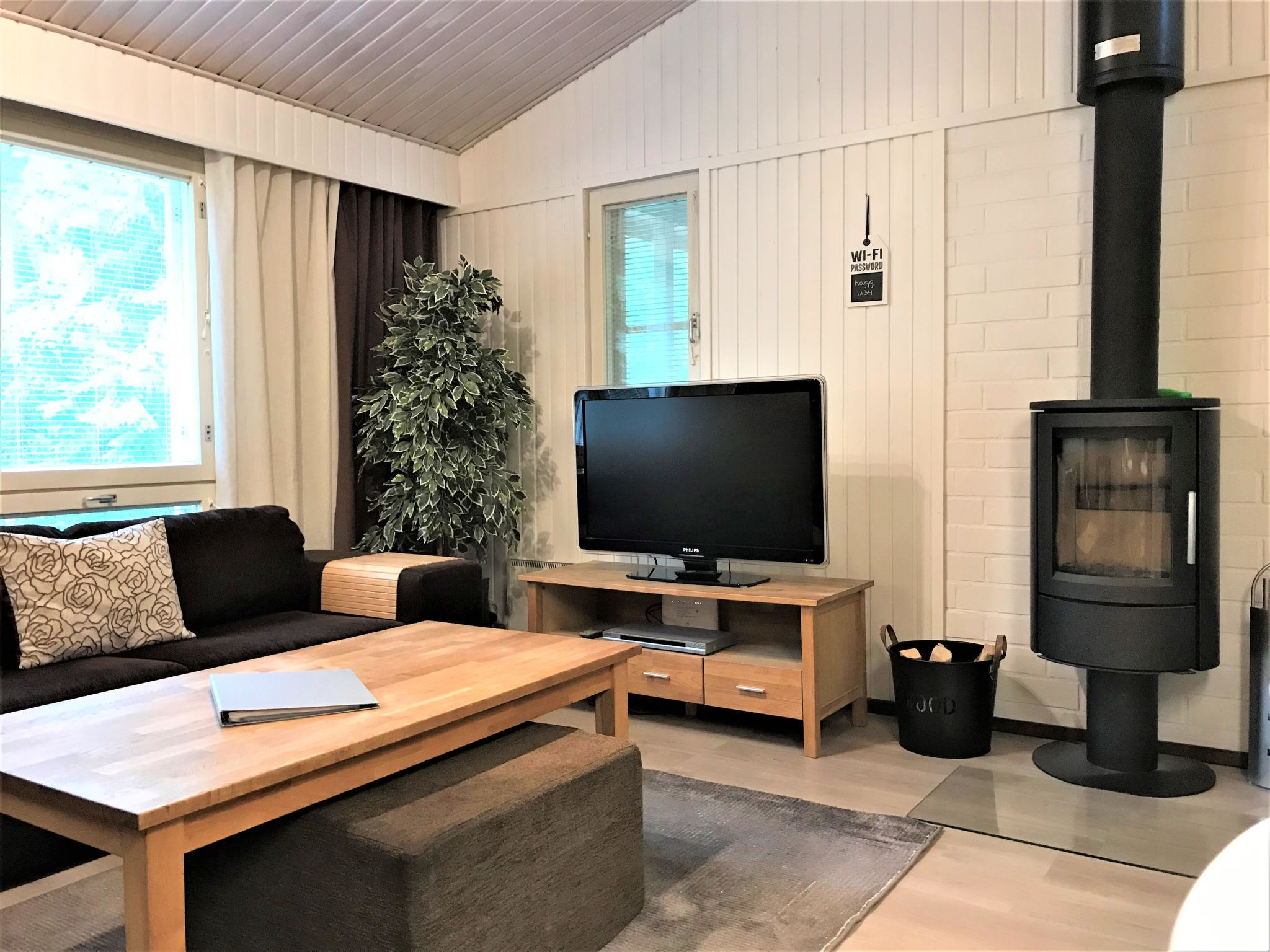 Una sala moderna con televisor de pantalla plana, sofá, mesa de centro y chimenea de leña.