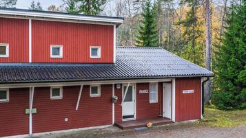 Un bâtiment rouge à deux étages, doté d’un toit plat, d’un porche à l’avant et d’une enseigne sur laquelle on peut lire « FAMILLE ».