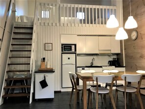 A compact kitchen with a dining area, a refrigerator, a microwave, and a stove. - Weekend family by Interhome (Sotkamo)
