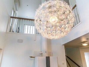 Un interior moderno con una lámpara esférica única, una escalera y vistas al exterior.