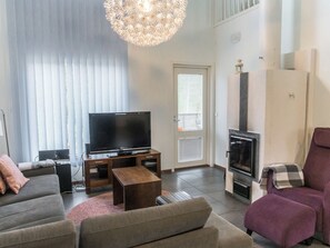 Una sala de estar con una televisión de pantalla plana, un sofá, una mesa de centro y una chimenea.