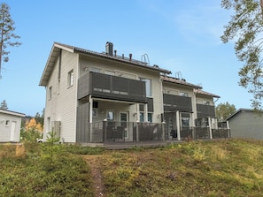 Una casa moderna de dos pisos con techo plano, ventanas amplias y un porche cubierto.