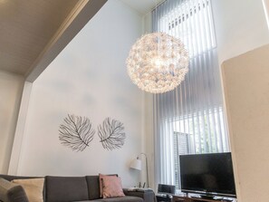 A living room with a sofa, a flat-screen TV, a decorative light fixture, and two wall art pieces.