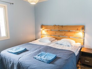 En pænt redt seng med et trægavl, to puder og sammenfoldede håndklæder på sengen.
