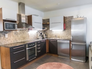 Una cocina moderna con refrigerador de acero inoxidable, horno integrado, microondas y lavavajillas.