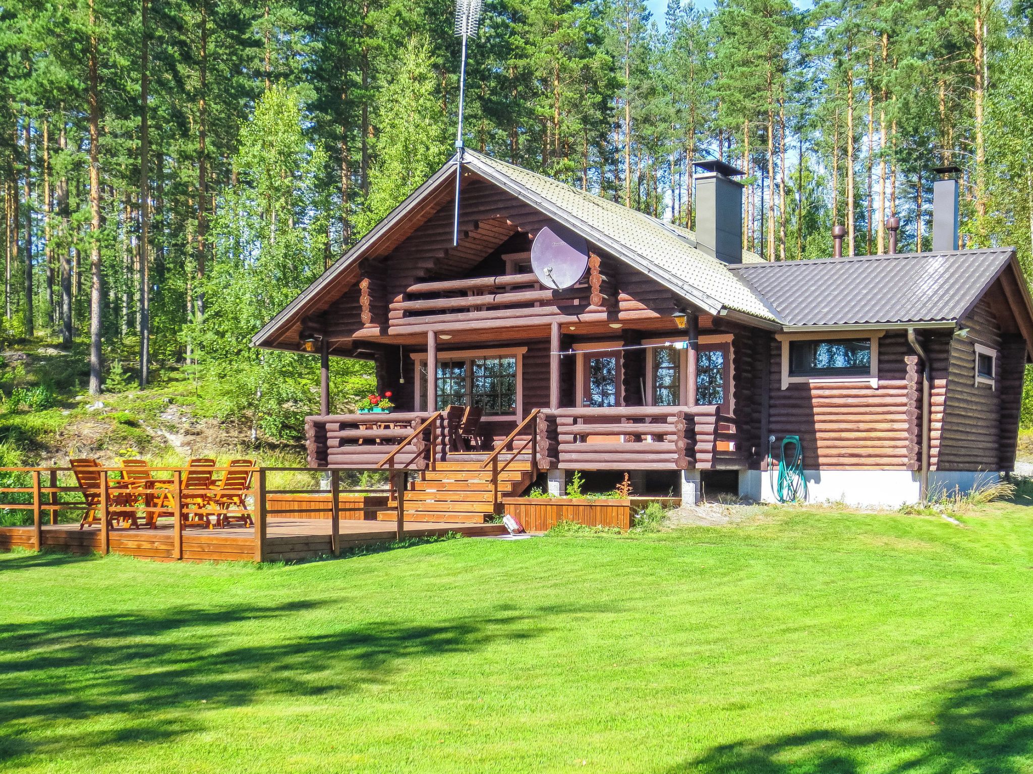 A log cabin with a porch, a satellite dish, and a chimney.