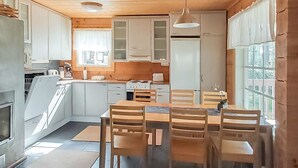 Eine moderne Küche mit Holzschränken, einem Esstisch mit Stühlen und einem großen Fenster für natürliches Licht.