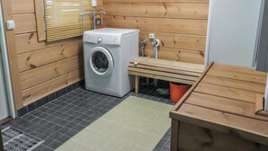 Ein kleiner Waschraum mit Waschmaschine, einer Bank und einem Holzschrank.