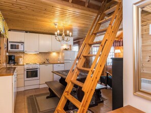A kitchen with wooden cabinets, a stove, a microwave, and a chandelier.