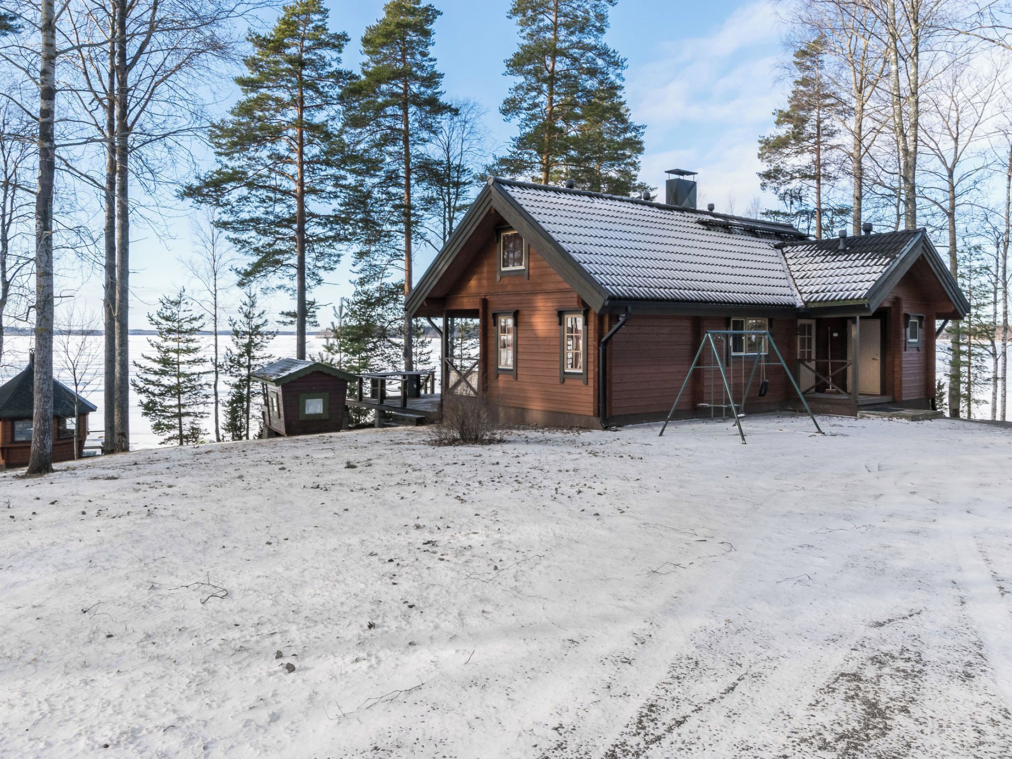 A cabin with a sloped roof, wooden walls, and a porch area.