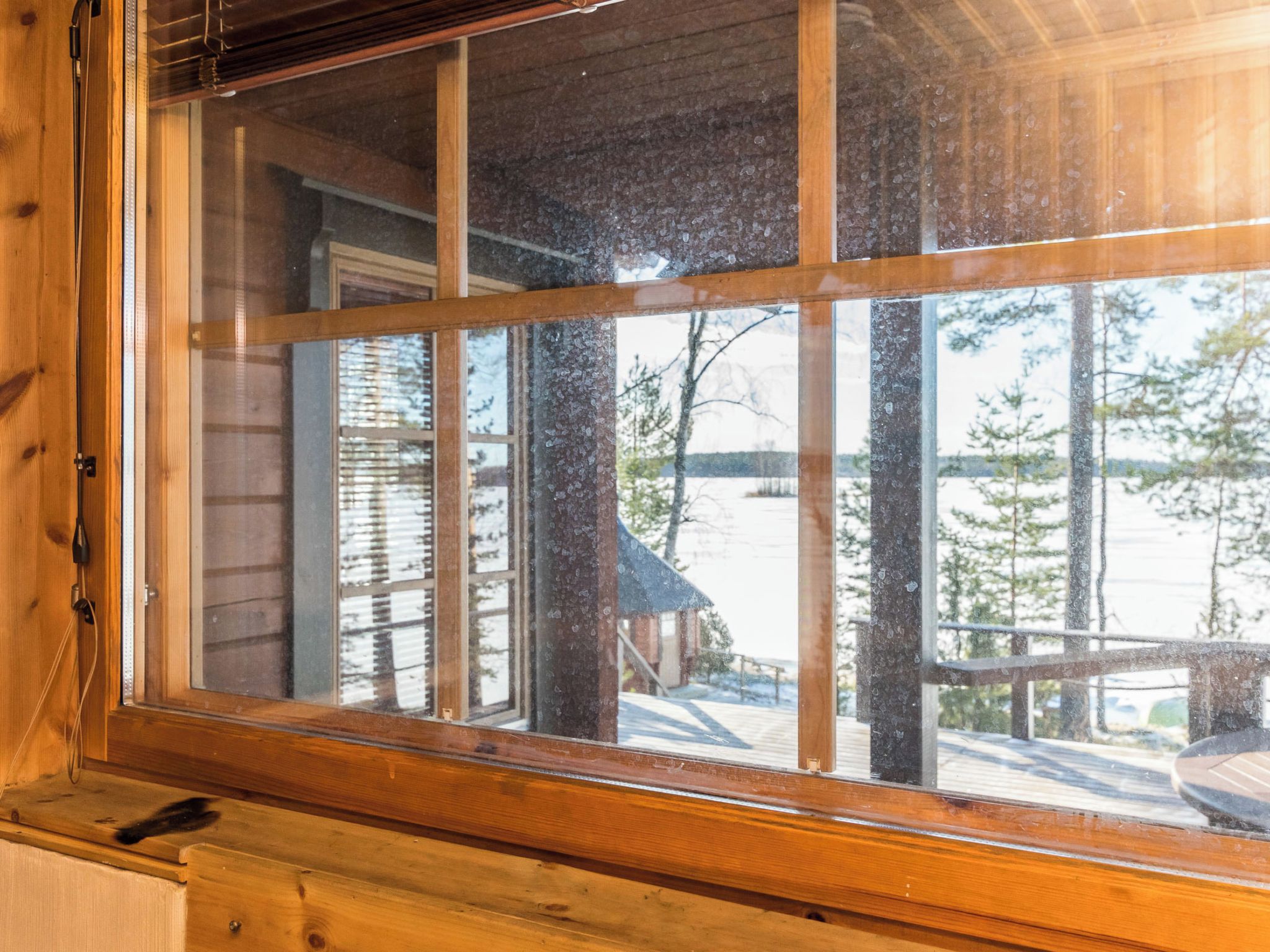 Une fenêtre à cadre en bois et à carreaux multiples, offrant une vue sur un paysage enneigé avec des arbres et un chalet.
