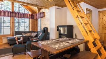 Interior acogedor de una cabaña con una mesa de comedor de madera, un sofá y una chimenea.